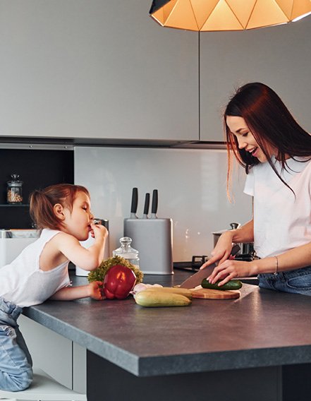 Little kid tasting chopped vegetables by mom