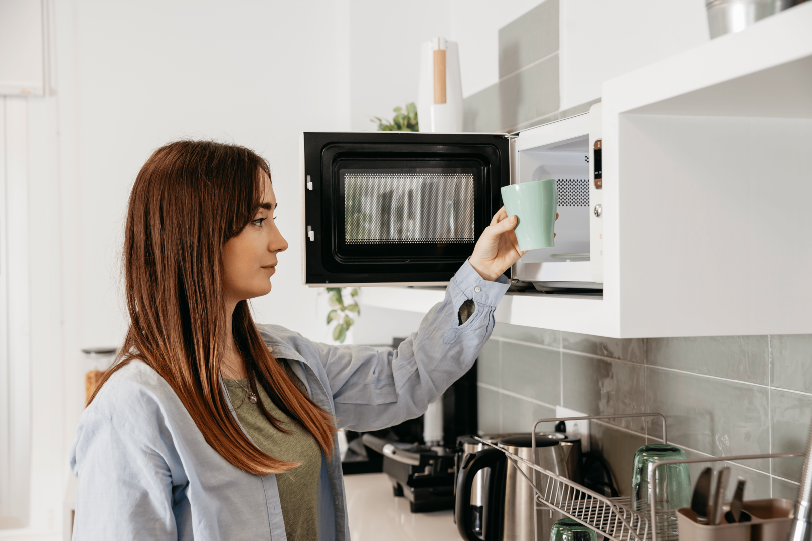 Woman placing mug in microwave